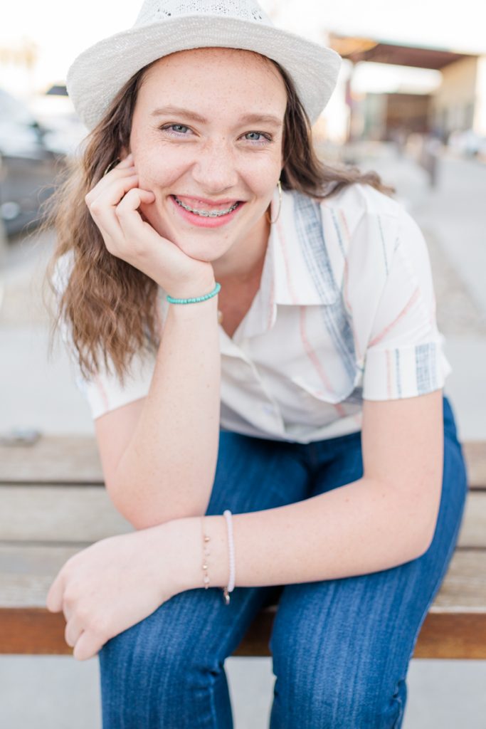 A high school senior girl wearing a hat smiles during a senior photo session with Salt Lake Photographer Jodi Cornwall Photography after reading how to choose a professional photographer.
