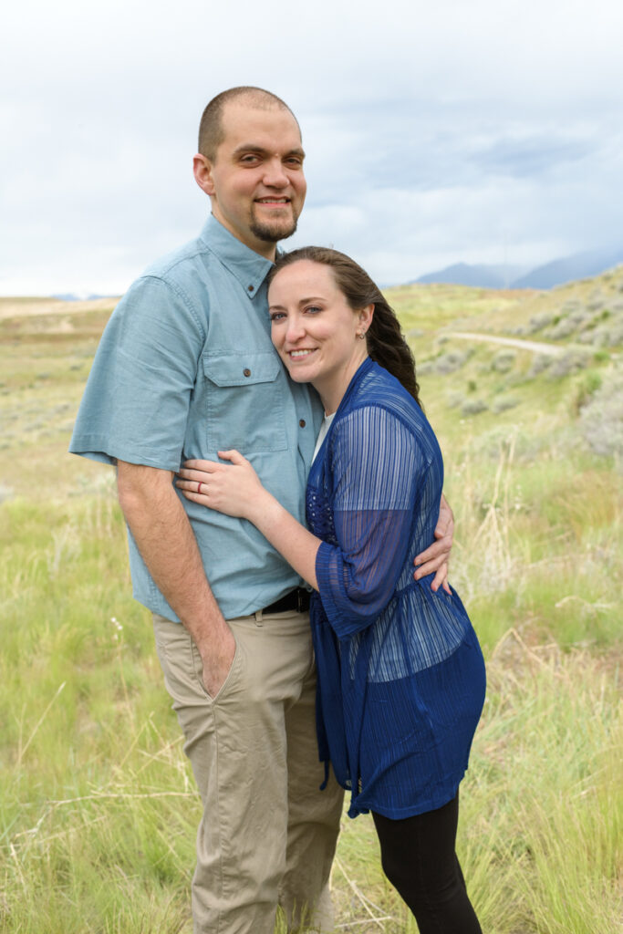 Married couple smiling in a field during a spring family photoshoot with Salt Lake Photographer Jodi Cornwall Photography.