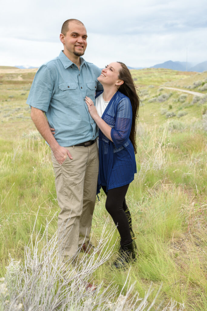 Married couple smiling in a field during a spring family photoshoot with Salt Lake Photographer Jodi Cornwall Photography.